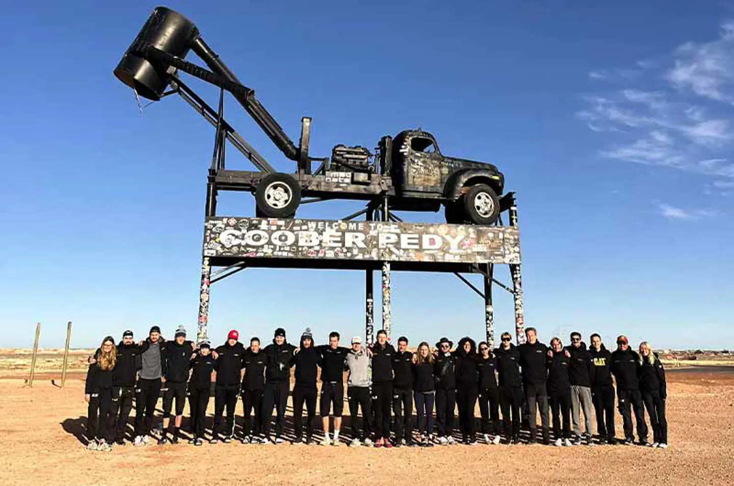 Hela teamet samlat framför skylten i Coober Pedy, Australien